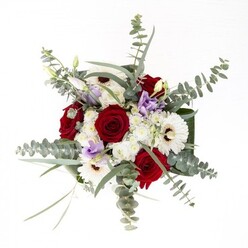 Expertly arranged by a Mottingham florist, this bouquet embodies balance and artistry, each flower contributing its unique personality while blending in seamless concert. At its center, robust red roses unfurl in elegant spirals, their richness symbolizing enduring affection and heartfelt connection. White gerberas, petals radiating outward like tiny suns, are anchored by deep brown centers, imparting both brightness and grounding to the overall composition. Sprigs of silvery eucalyptus punctuate the upper reaches of the arrangement, casting gentle shadows and lending a subtle, invigorating fragrance reminiscent of a stroll through Elmstead Woods. Scattered among these, soft lilac lisianthus blooms-paired with slender buds-provide a modern, whimsical note, their hues echoing the pastel skies often seen over Mottingham Common at dusk. Fluffy white filler flowers cluster like pearls beneath the main blossoms, enriching the texture and lending a playful softness. The clear glass vase offers a glimpse of fresh, green stems and clear water, underscoring a feeling of vitality and renewal. Framed by glossy, wide green leaves wrapped around the base, this bouquet is perfectly suited to anniversaries, housewarmings, or moments calling for comfort-an arrangement that reflects both the expertise and heartfelt care of Mottingham Florist and the welcoming neighbourly spirit of the area.
